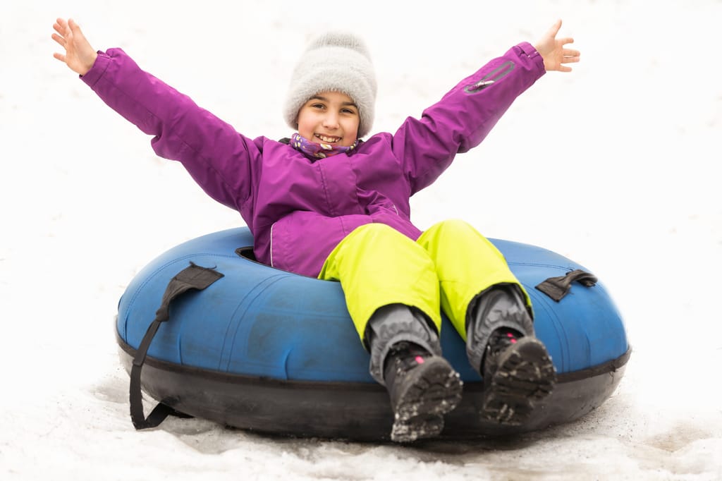 Child riding on tube, little girl during tubing in winter park.