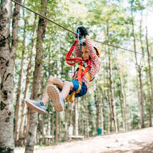 Boy goes down the zip line in the adventure park.