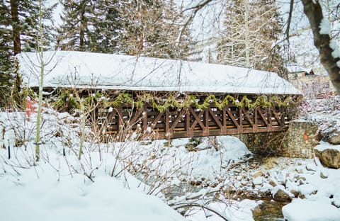 A traditional wooden bridge covered in snow and decorated with fresh garland