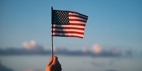 Man holding american USA flag in the sunset. Independence Day or traveling in America concept.