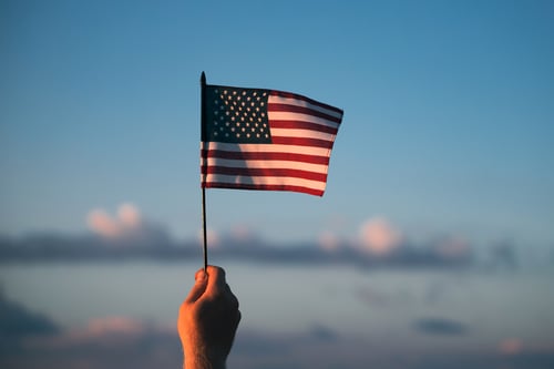 Man holding american USA flag in the sunset. Independence Day or traveling in America concept.